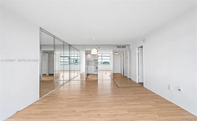 a view of an empty room with wooden floor and a window