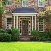 a view of a house with brick walls and a yard with plants
