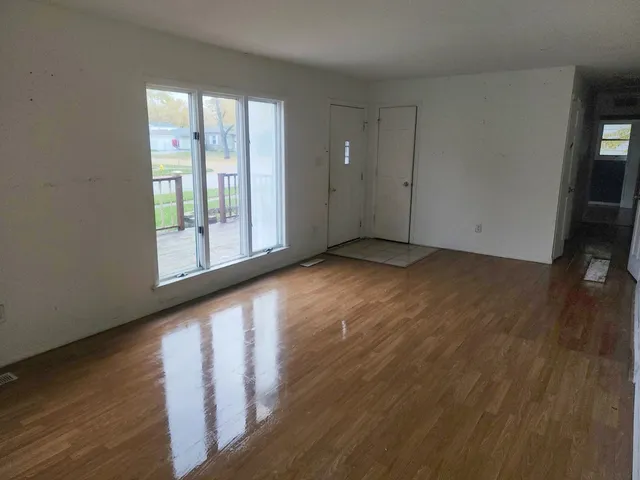 a view of an empty room with wooden floor and a window
