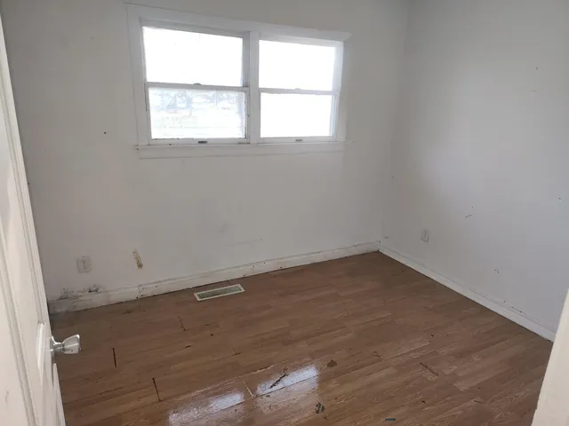 an empty room with wooden floor and window