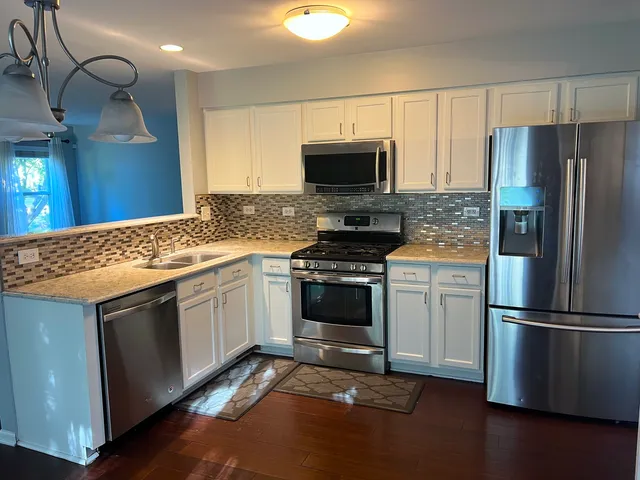 a kitchen with stainless steel appliances granite countertop a stove a refrigerator and a microwave