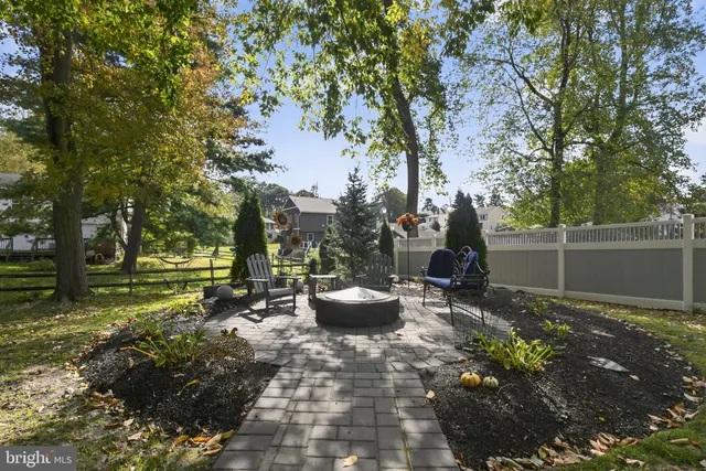 a view of a backyard with table and chairs potted plants and large tree