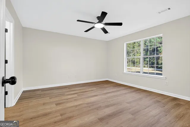 a view of an empty room with wooden floor and a window