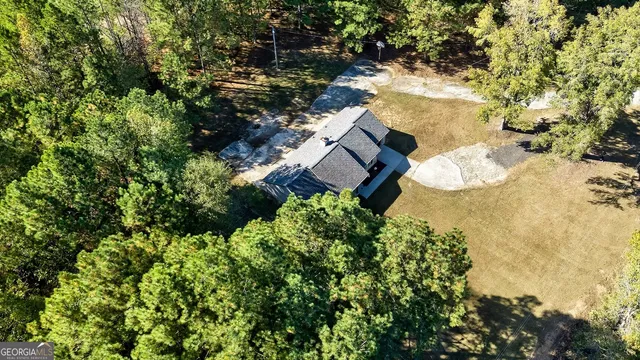 an aerial view of residential house with outdoor space and trees all around