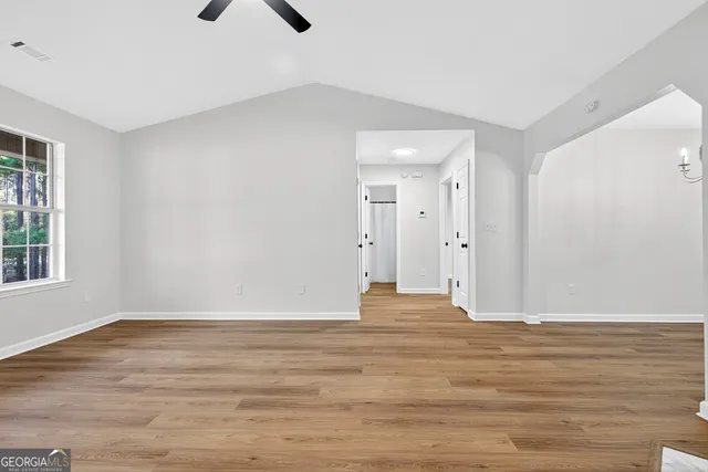 a view of an empty room with wooden floor and a window