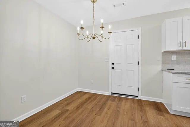 a view of an empty room with chandelier fan and wooden floor