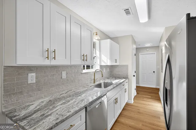 a kitchen with granite countertop a sink refrigerator and cabinets