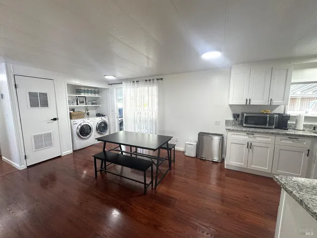 a living room with furniture a dining table wooden floor and a window