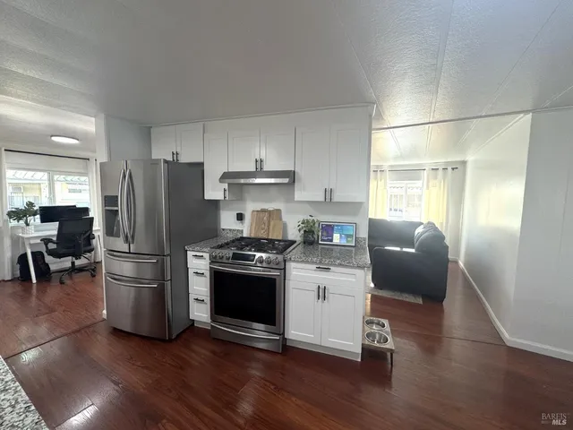 a kitchen with a refrigerator stove and wooden floor