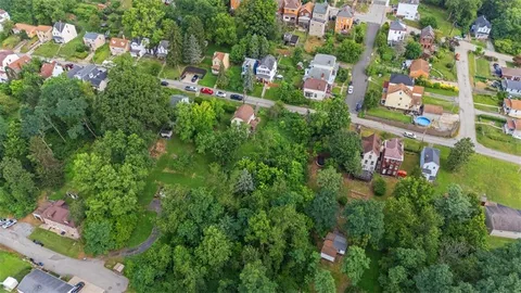 an aerial view of residential house with outdoor space and trees all around
