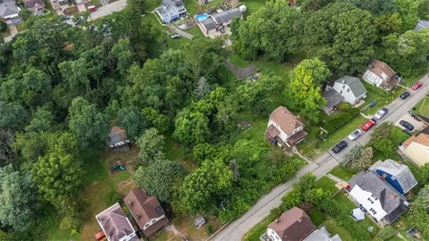 an aerial view of a house with a yard and large trees