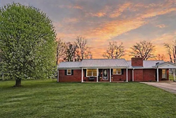 a view of a brick house with a big yard and large trees