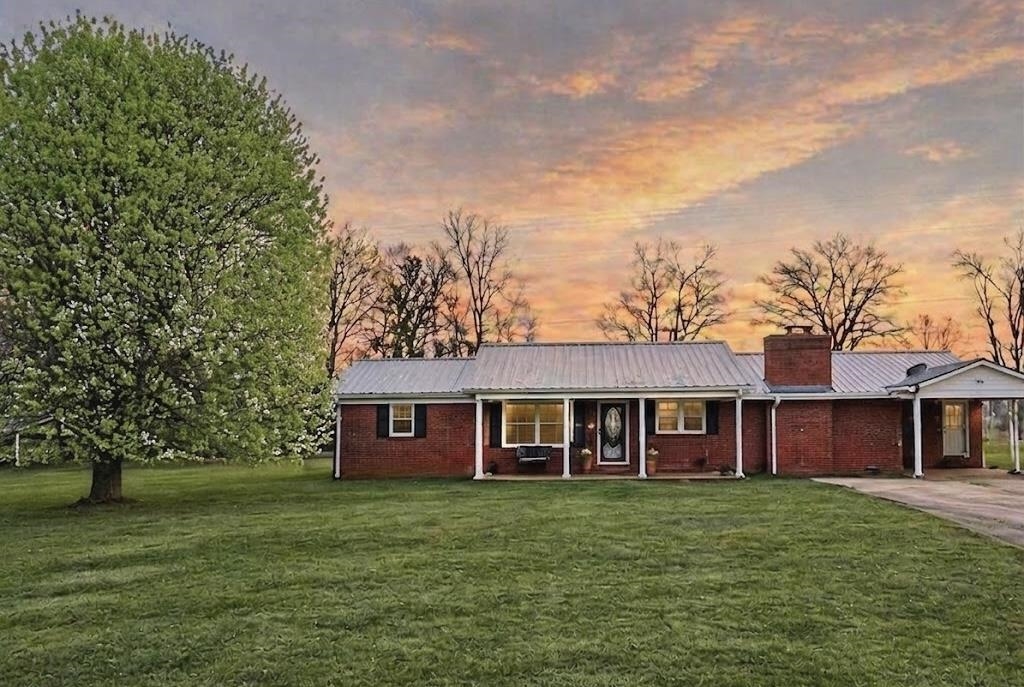 a view of a brick house with a big yard and large trees