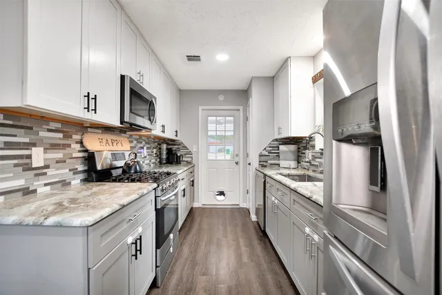 a kitchen with stainless steel appliances granite countertop a stove sink and cabinets