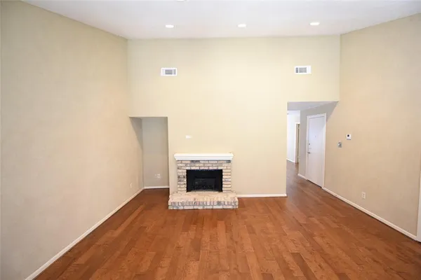 a view of empty room with wooden floor and fireplace
