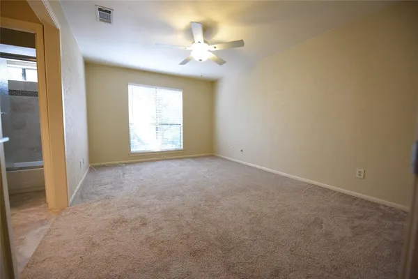 an empty room with windows and ceiling fan