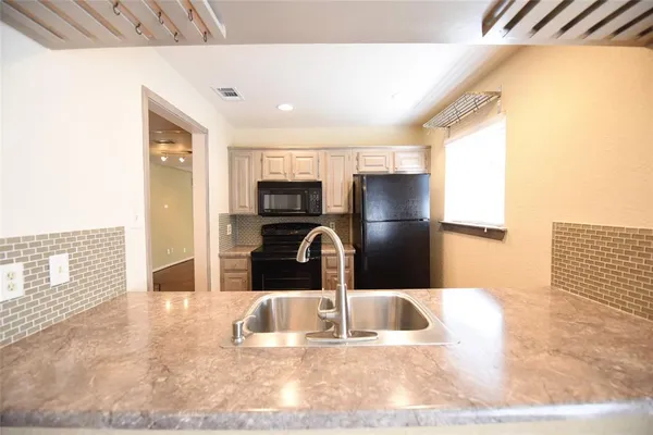 a kitchen with granite countertop a refrigerator and a stove top oven