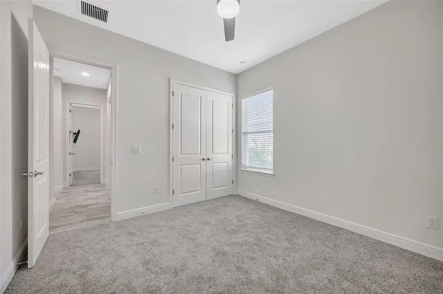 an empty room with windows and fan