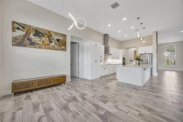 a kitchen with stainless steel appliances kitchen island granite countertop a refrigerator a sink and white cabinets