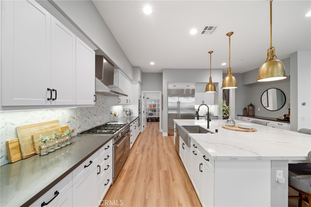 17042 Meteor Way Riverside, CA 92503 - Photo 12 of 75 a large kitchen with kitchen island a stove a sink a oven and a dining table with wooden floor