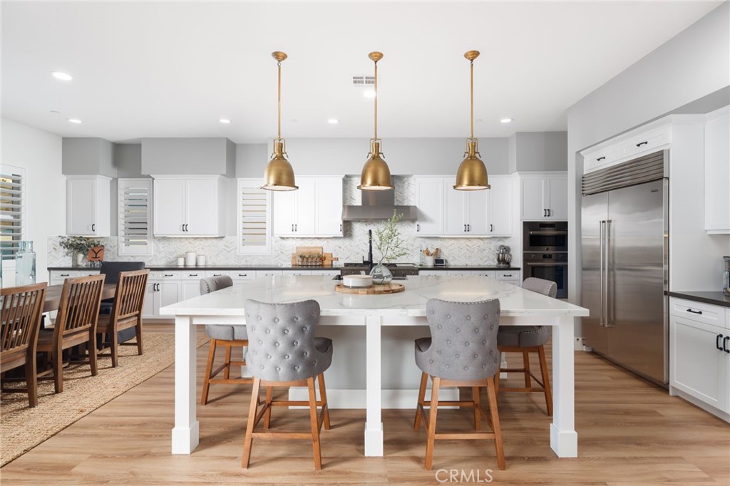 17042 Meteor Way Riverside, CA 92503 - Photo 9 of 75 a kitchen with stainless steel appliances kitchen island granite countertop a table chairs and white cabinets