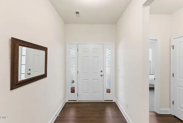 an empty room with wooden floor cabinet and windows