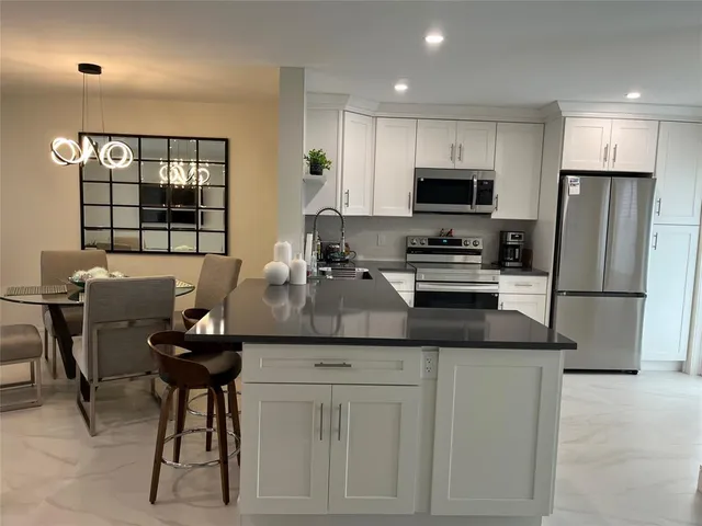 a kitchen with stainless steel appliances granite countertop a sink a stove a refrigerator and a dining table with wooden floor