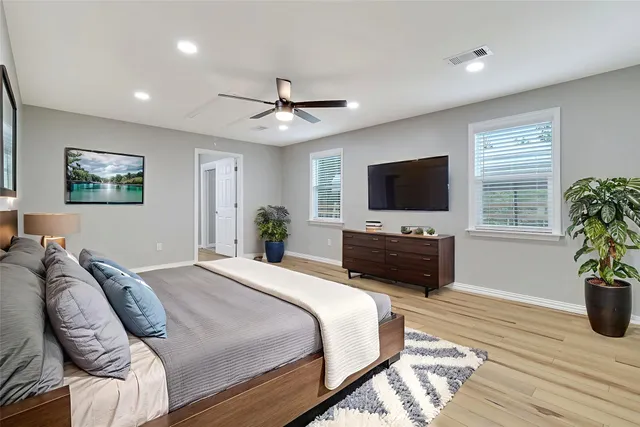 a spacious bedroom with a bed and a flat screen tv