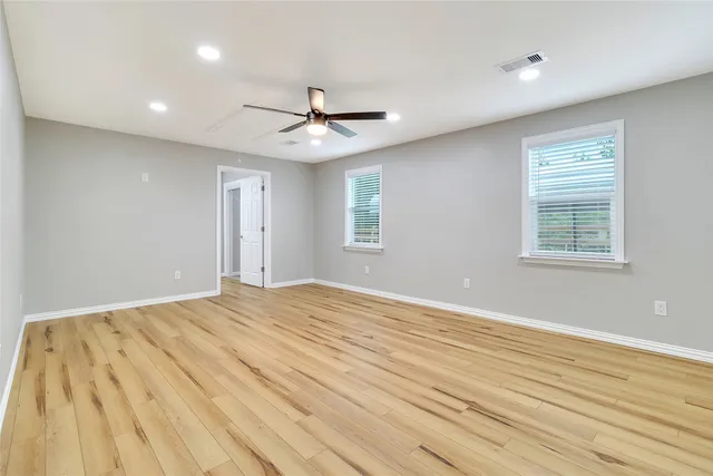 a view of empty room with wooden floor and fan