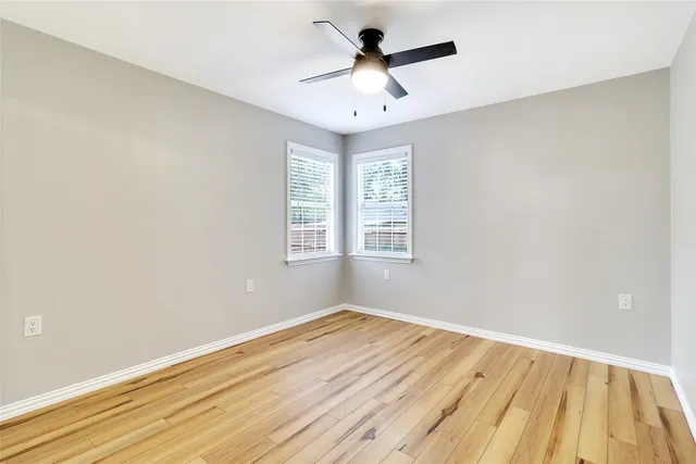 an empty room with a window and a ceiling fan