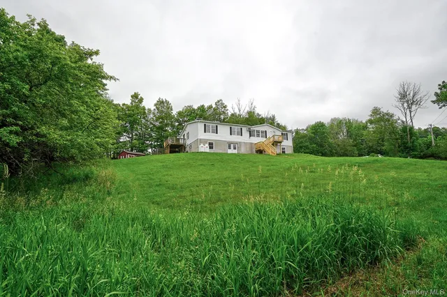a view of a house with a big yard and large trees