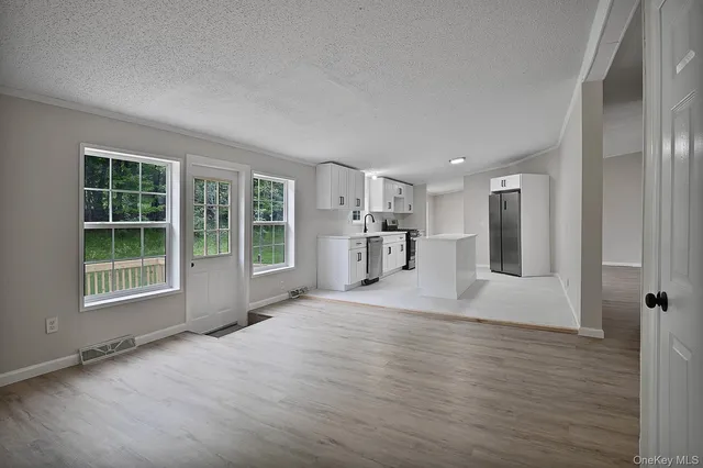 a view of an empty room with a window and wooden floor