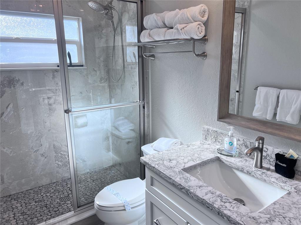 6154 Midnight Pass Road, Unit A11 Sarasota, FL 34242 - Photo 14 of 22 a bathroom with a granite countertop sink a toilet and shower