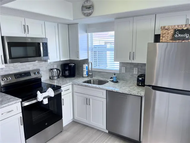 a kitchen with white cabinets and black appliances