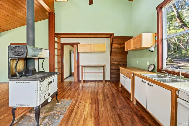 a kitchen with stainless steel appliances granite countertop a stove top oven a sink with wooden cabinets and glass windows