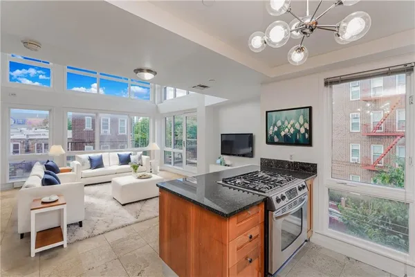 a open kitchen with stainless steel appliances granite countertop a stove and a view of living room