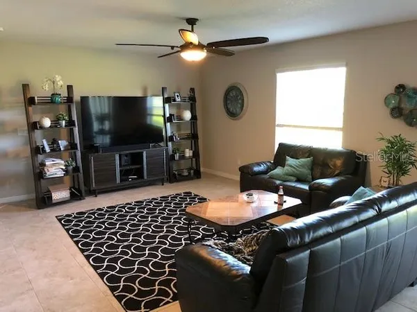 a living room with furniture a flat screen tv and a window