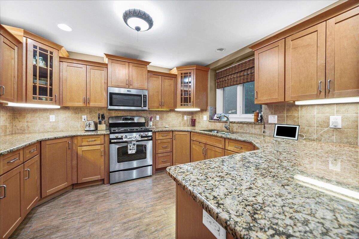 8751 Bridgewater Court Crown Point, IN 46307 - Photo 27 of 49 a kitchen with stainless steel appliances granite countertop a stove sink microwave and cabinets