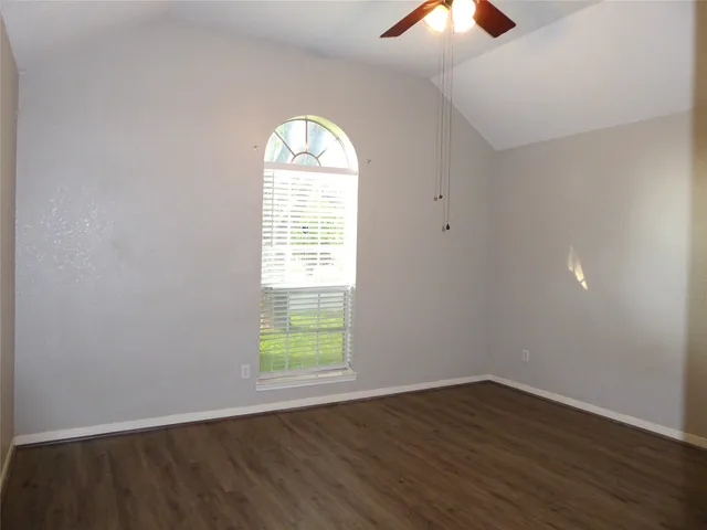 an empty room with wooden floor closet and windows