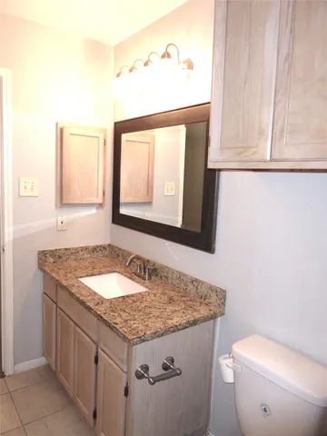 a bathroom with a granite countertop sink and a toilet