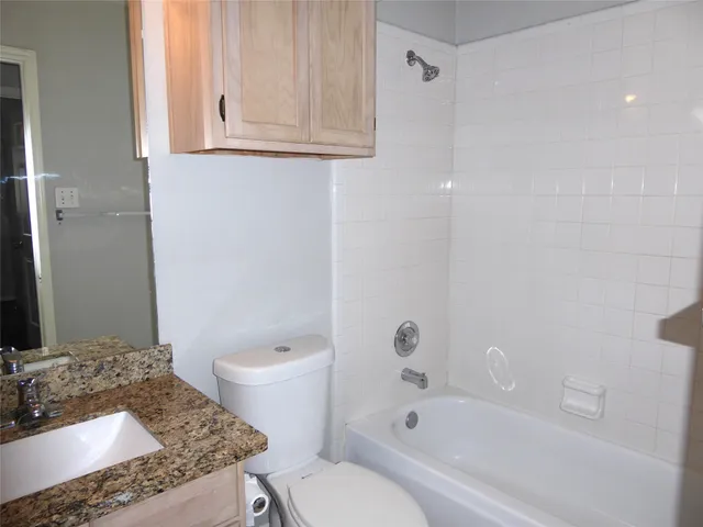 a bathroom with a granite countertop sink a toilet and shower