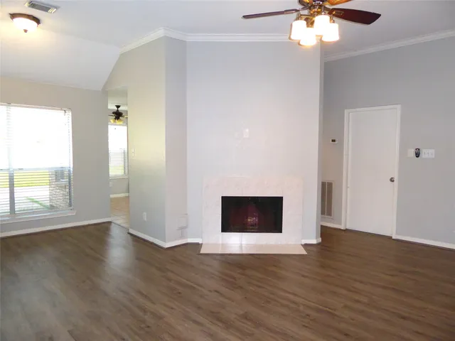 an empty room with wooden floor a ceiling fan and windows
