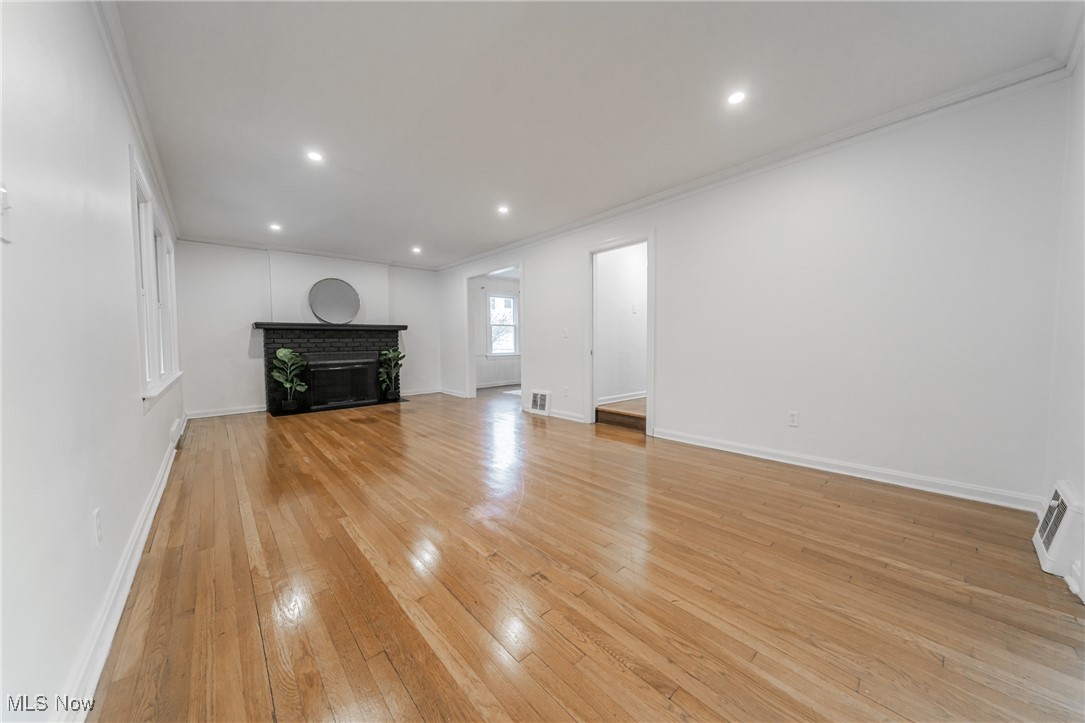 1391 Avondale Road Cleveland, OH 44121 - Photo 7 of 46 Unfurnished living room featuring baseboards, recessed lighting, a brick fireplace, and light wood finished floors