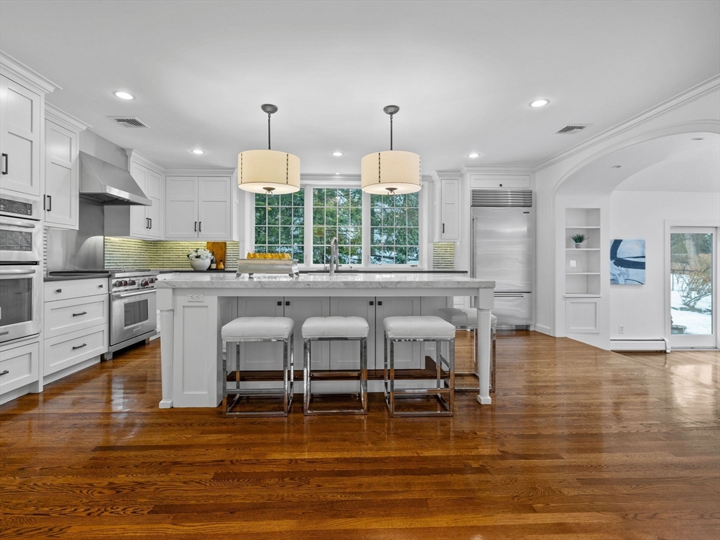 10 Livingston Road Wellesley, MA 02482 - Photo 8 of 36 a kitchen with stainless steel appliances granite countertop a stove top oven a sink dishwasher a dining table and chairs with wooden floor