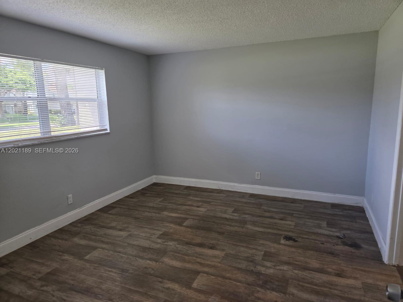 8060 North Colony Circle, Unit 103 Tamarac, FL 33321 - Photo 7 of 8 a view of an empty room with wooden floor and a window