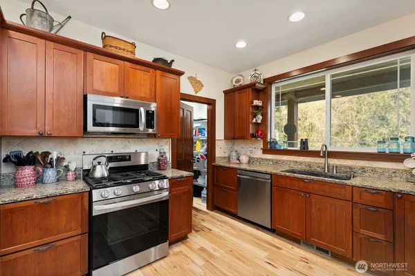 a open kitchen with stainless steel appliances granite countertop a stove a sink dishwasher and a wooden floor