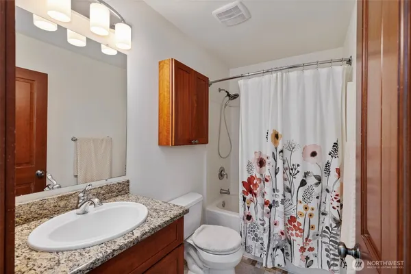 a bathroom with a granite countertop sink toilet and a mirror