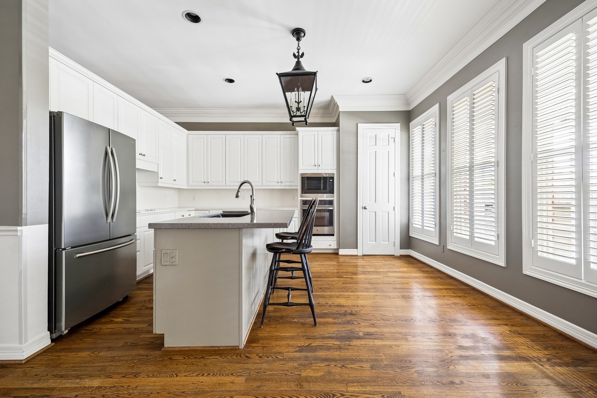 6022 Burgoyne Road Houston, TX 77057 - Photo 6 of 30 Bright, updated kitchen with white cabinetry, center island, stainless steel appliances, and a wall of windows overlooking the outdoor spaces.