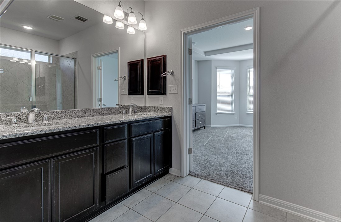 2709 Fortezza Way Round Rock, TX 78665 - Photo 16 of 39 a bathroom with a granite countertop sink a mirror and a shower