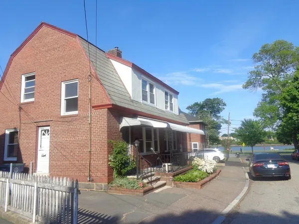 a view of a brick house with a yard and table and chairs under an umbrella